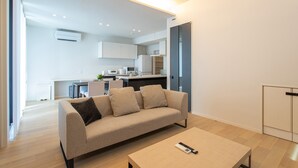 Un salon moderne avec un canapé, une table basse et une cuisine en arrière-plan.