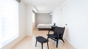 Une chambre à coucher moderne et minimaliste, avec un lit, une chaise et une petite table.