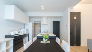 Une cuisine moderne avec des meubles blancs, une table à manger noire et une plante en pot.