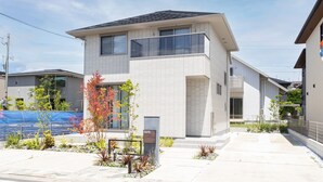 Un immeuble résidentiel moderne à deux étages, doté d’un toit plat, de grandes fenêtres et d’un petit balcon.