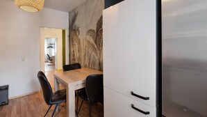 Eine moderne Küche mit einem Holztisch, schwarzen Stühlen, einem Edelstahlkühlschrank und einer strukturierten Wandmalerei.