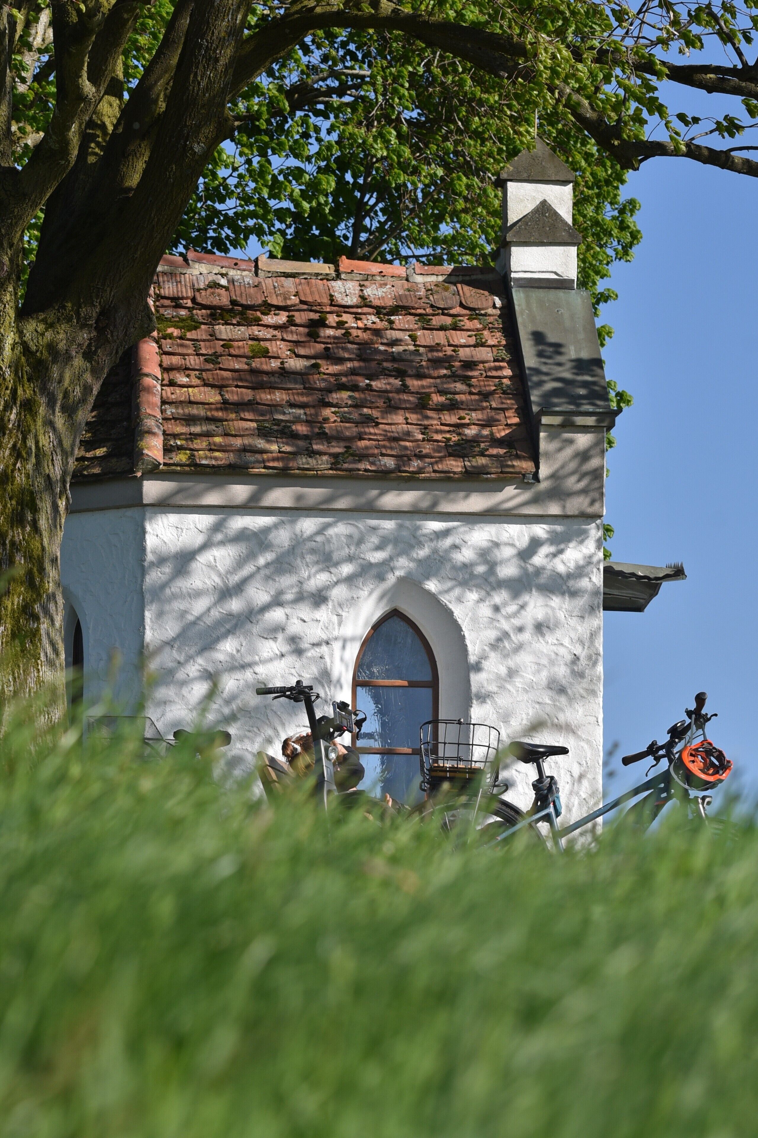 A white building with a red-tiled roof, a small tower, and an arched window.