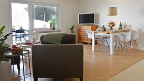 Ein modernes Wohnzimmer mit Sofa, Esstisch und Fernseher.