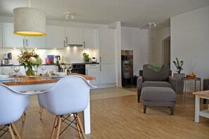 Una cocina moderna con armarios blancos, una mesa de comedor de madera y dos sillas.