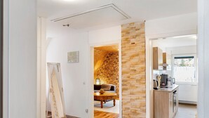 Una cocina moderna con pared de piedra, piso de madera y zona de comedor con mesa y sillas.