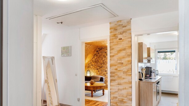 Una cocina moderna con pared de piedra, piso de madera y zona de comedor con mesa y sillas.