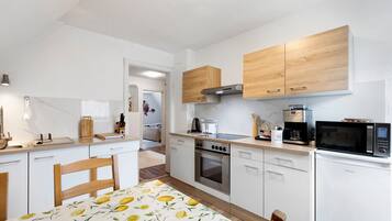A modern kitchen with white cabinets, a built-in oven, microwave, and coffee maker.