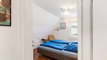 Un dormitorio con cama, una silla, un cuadro en la pared y una ventana con vistas.