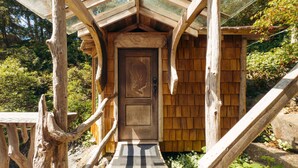 Une structure en bois dotée d’une porte, d’un escalier en bois et d’un toit en verre.
