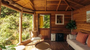 L’intérieur d’un chalet accueillant, avec un plafond en bois, un canapé, un fauteuil, une petite table et une plante en pot.