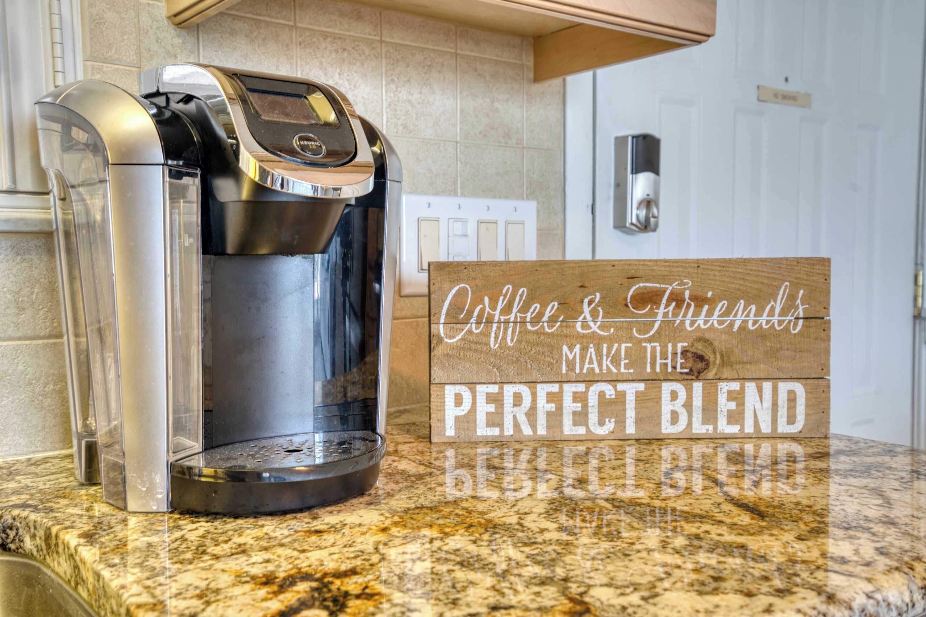 Una cafetera sobre una encimera de granito con un letrero que dice 'Coffee & Friends Make the Perfect Blend'.