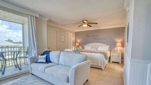 Une chambre à coucher avec un lit, un canapé, un ventilateur de plafond et une vue sur l’extérieur.