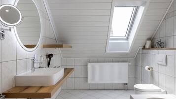 A modern bathroom with a skylight, a wooden vanity, a round mirror, a toilet, and a bathtub.