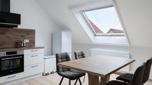 A modern kitchen with a skylight, a dining area with a wooden table and chairs, and a built-in oven. - Rhön-Kutscher Apartment with Mountain View, Terrace and Wi-Fi (36419 Buttlar)