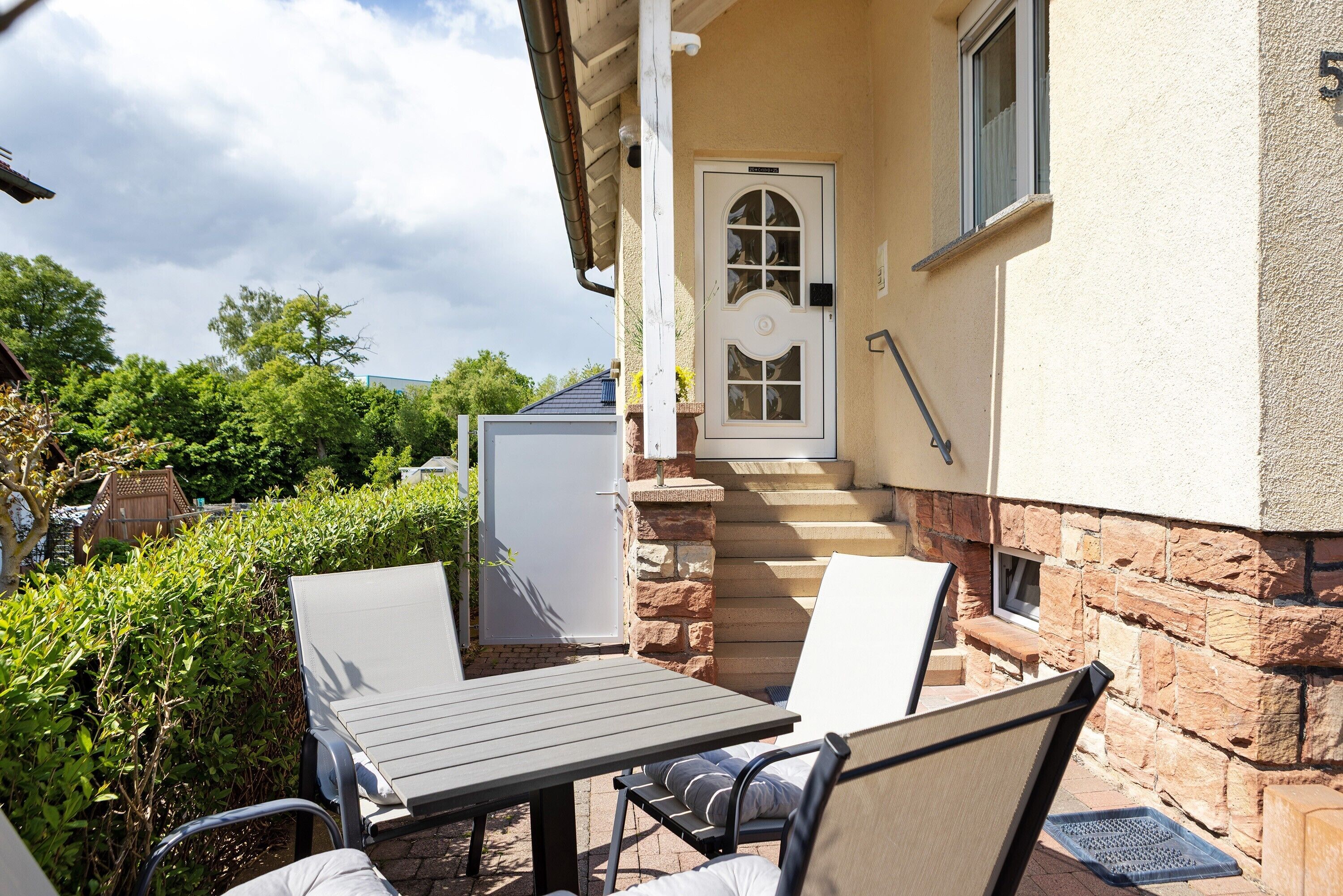 A patio with a table and chairs, a door, and a stone wall.