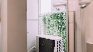 A room with a white air conditioning unit, a white door, and a green leafy wall. - Minimalist Loft 403 (Osaka)