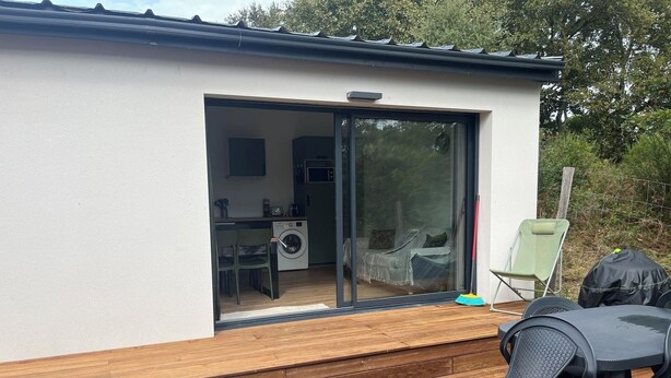 Une petite maison moderne dotée d’une porte-fenêtre coulissante qui donne sur une cuisine et un espace de vie.