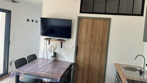 Une cuisine moderne dotée d’un téléviseur encastré, de meubles en bois et d’un coin repas avec une table et des chaises.