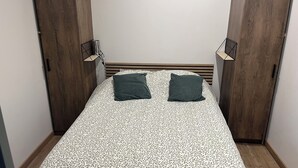 Une chambre à coucher avec une couvre-lit à motifs, deux oreillers, une tête de lit en bois et deux armoires en bois.
