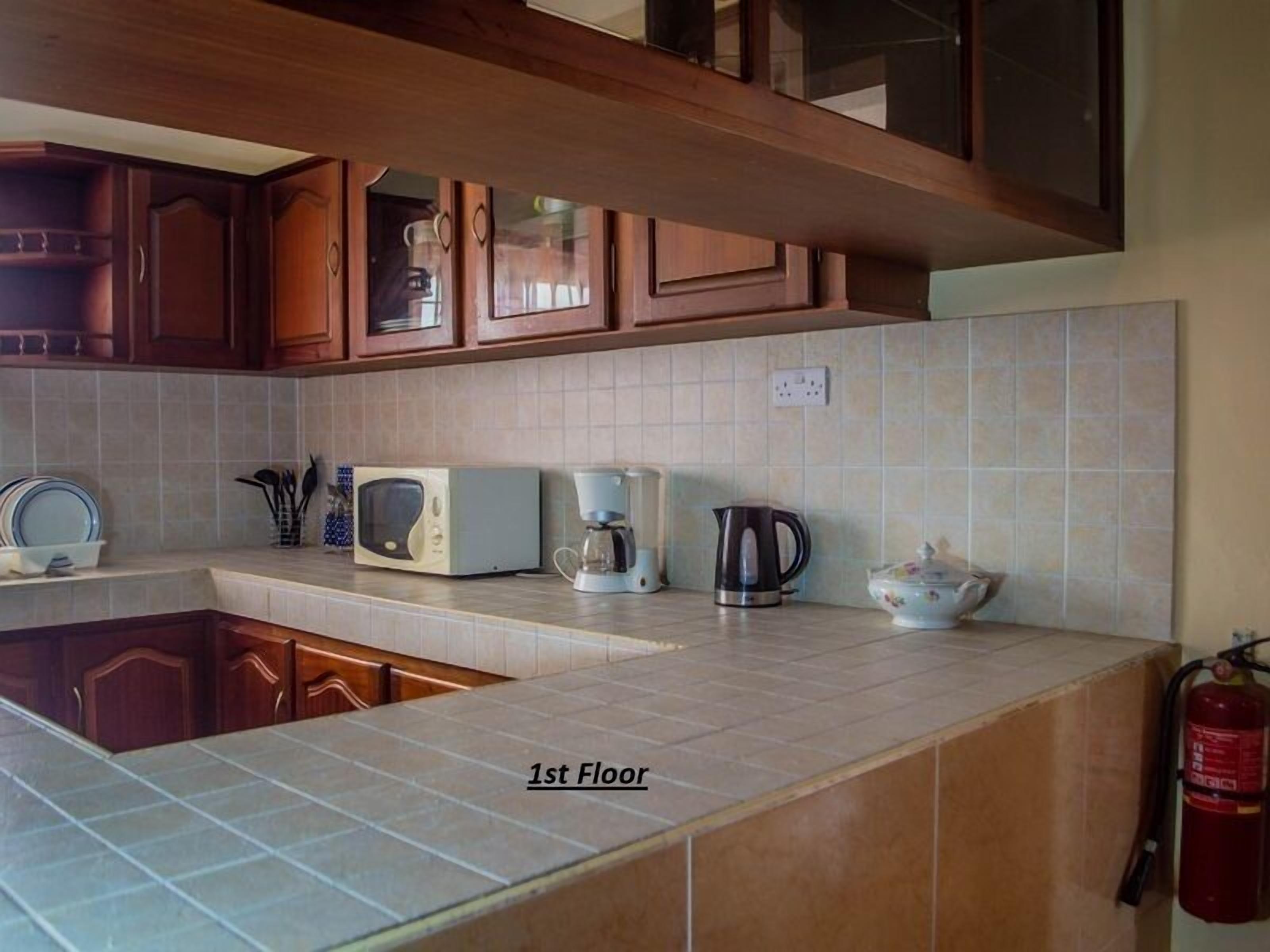 A kitchen with wooden cabinets, a microwave, a coffee maker, and a kettle on the countertop.