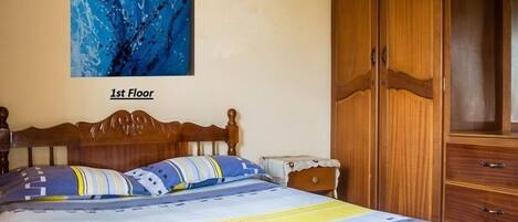 Un dormitorio con una cama de madera, un cuadro abstracto azul grande en la pared y un armario.