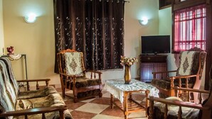 A living room with a checkered floor, two armchairs, a sofa, a coffee table, a TV, and curtains. - Villa Nass (Flic-en-Flac)