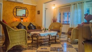 A cozy lounge area with wicker furniture, a checkered floor, and a mirror on the wall. - Villa Nass (Flic-en-Flac)