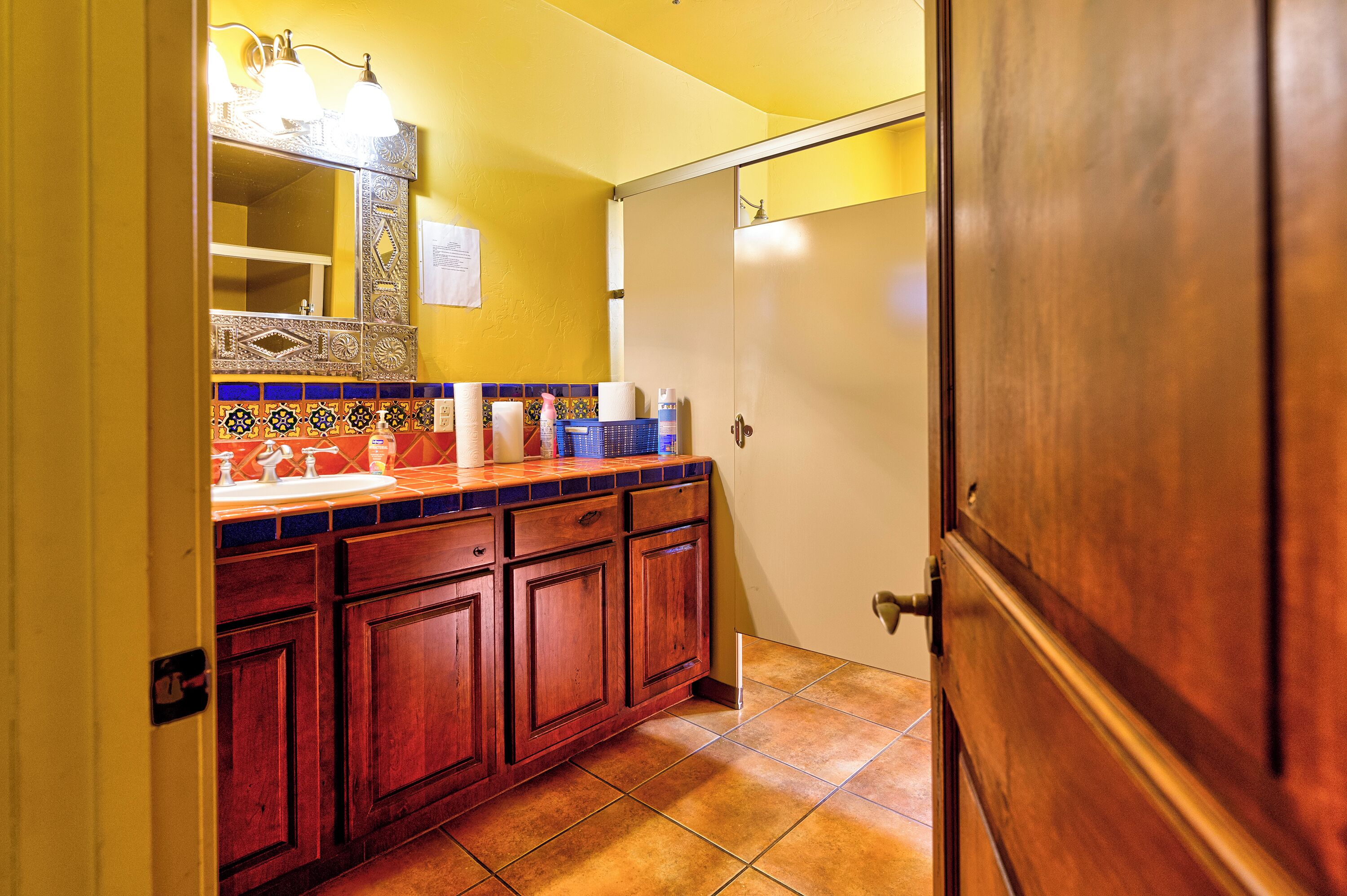 A bathroom with a wooden vanity, a sink, and a mirror with decorative tiles.