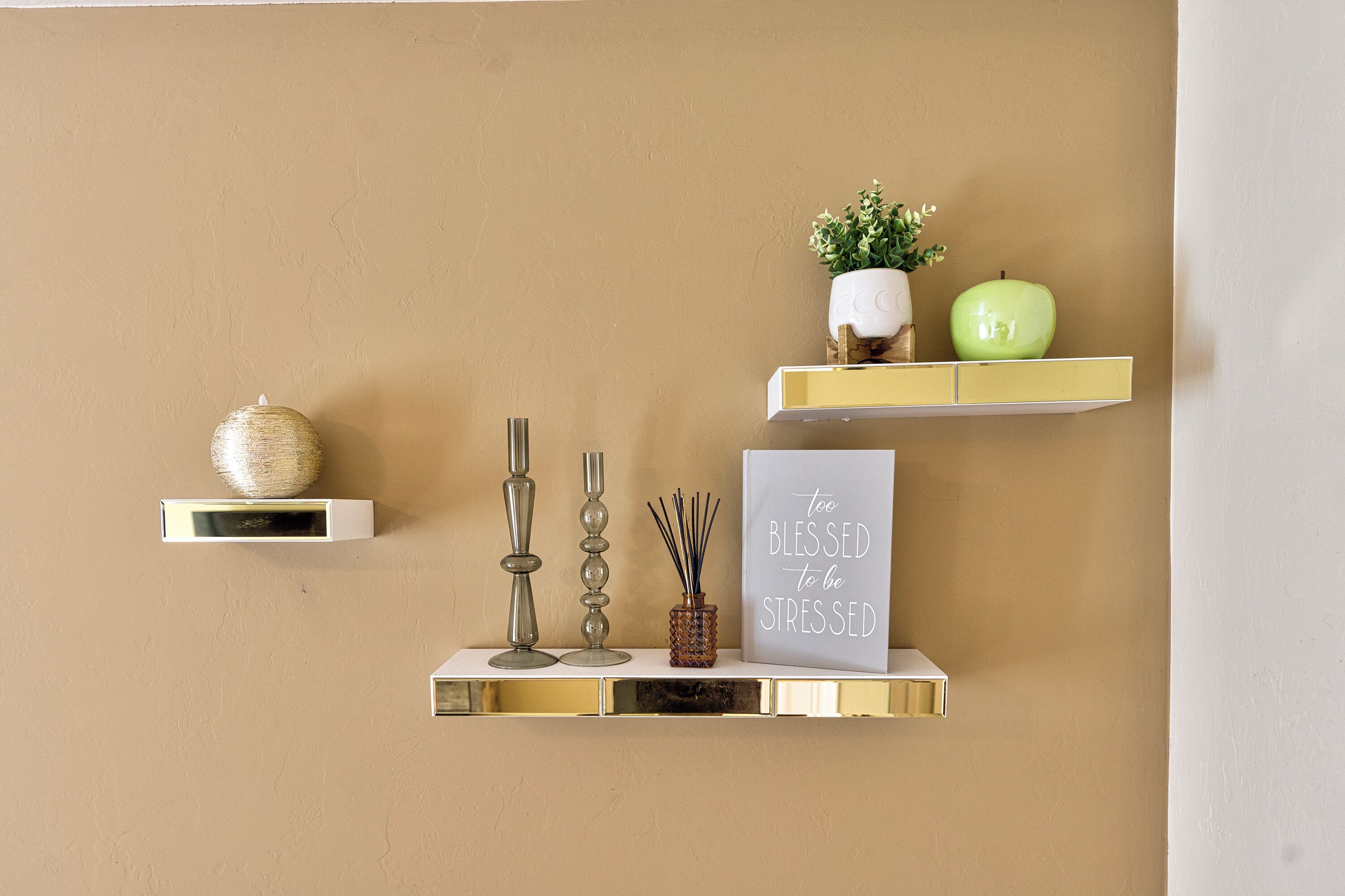 Una pared con tres estantes mostrando objetos decorativos.