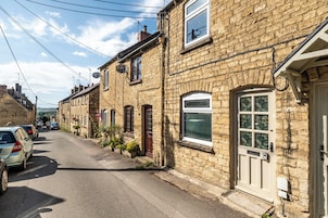 Una calle estrecha flanqueada por edificios de piedra tradicionales, cada uno con un estilo arquitectónico diferente, con varias ventanas y puertas.