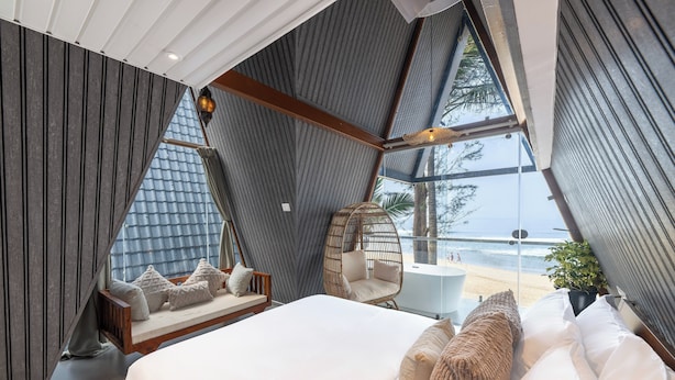 A bedroom with a large bed, a hanging chair, and a view of the beach. - The Rose Goa Beach Resort (Canacona)