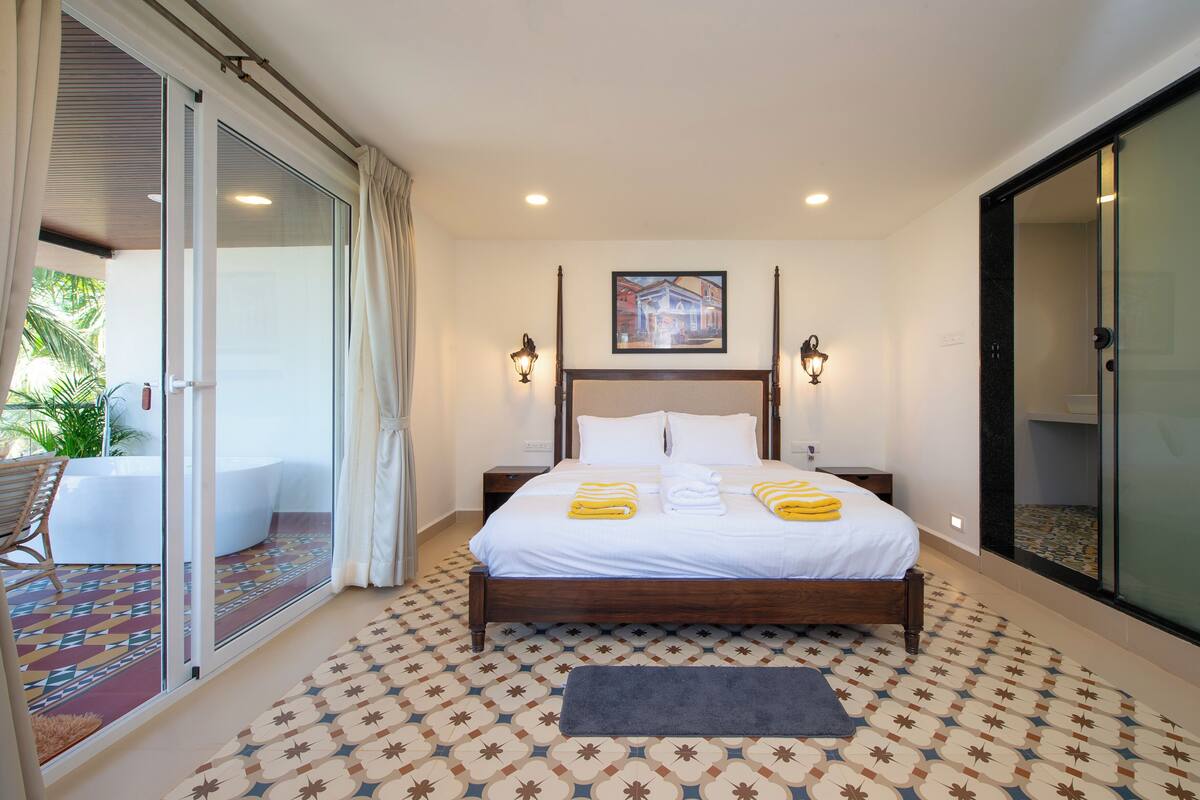Habitación de hotel con una cama grande, un balcón con vistas y un suelo estampado.