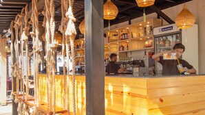 A bar area with wooden seating and rope decorations, shelves with bottles, and a sign reading "BLUE STAR". - The Rose Goa Beach Resort (Canacona)