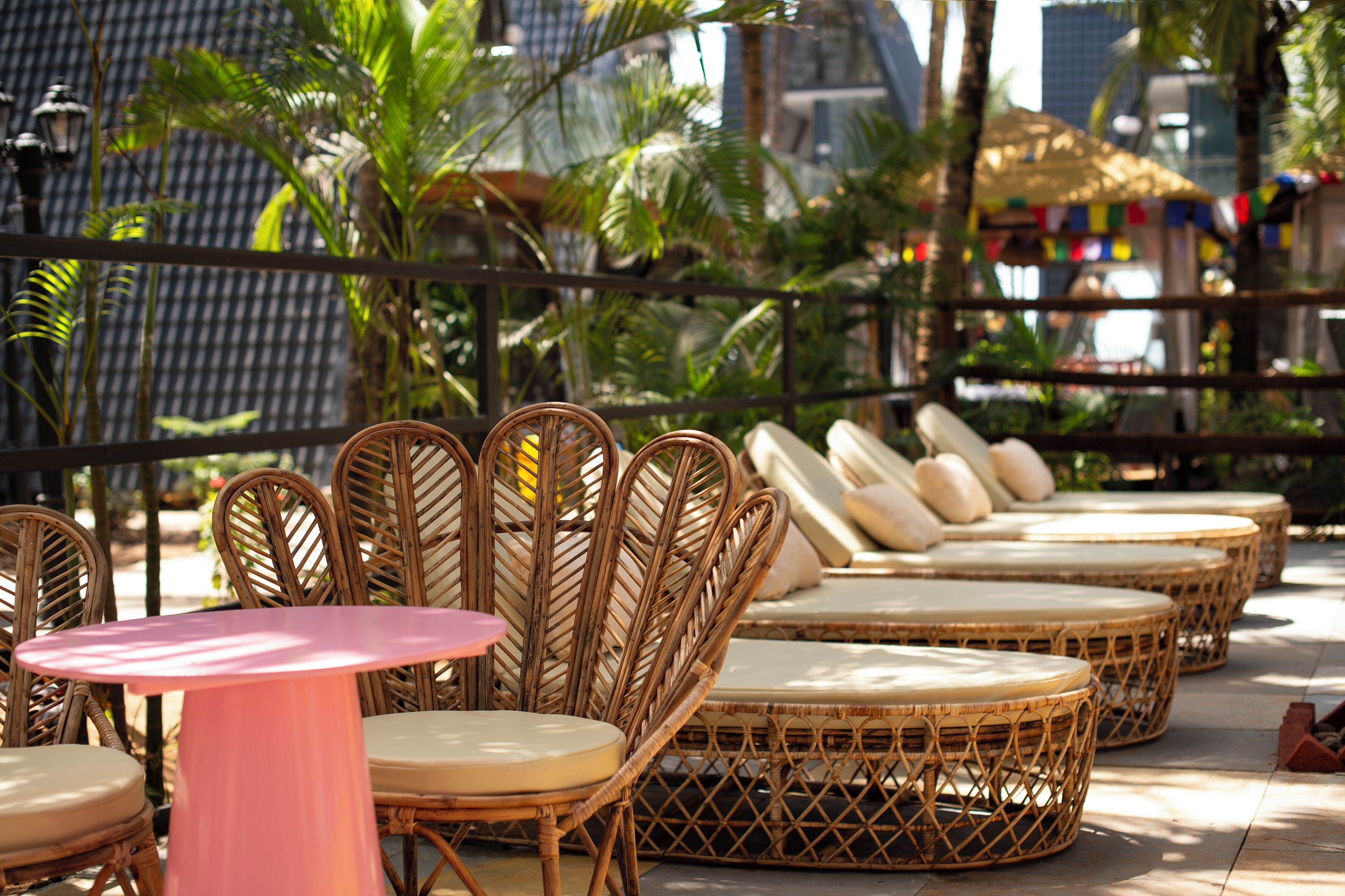 Wicker furniture with cushions, a round table, and a view of buildings in the background.