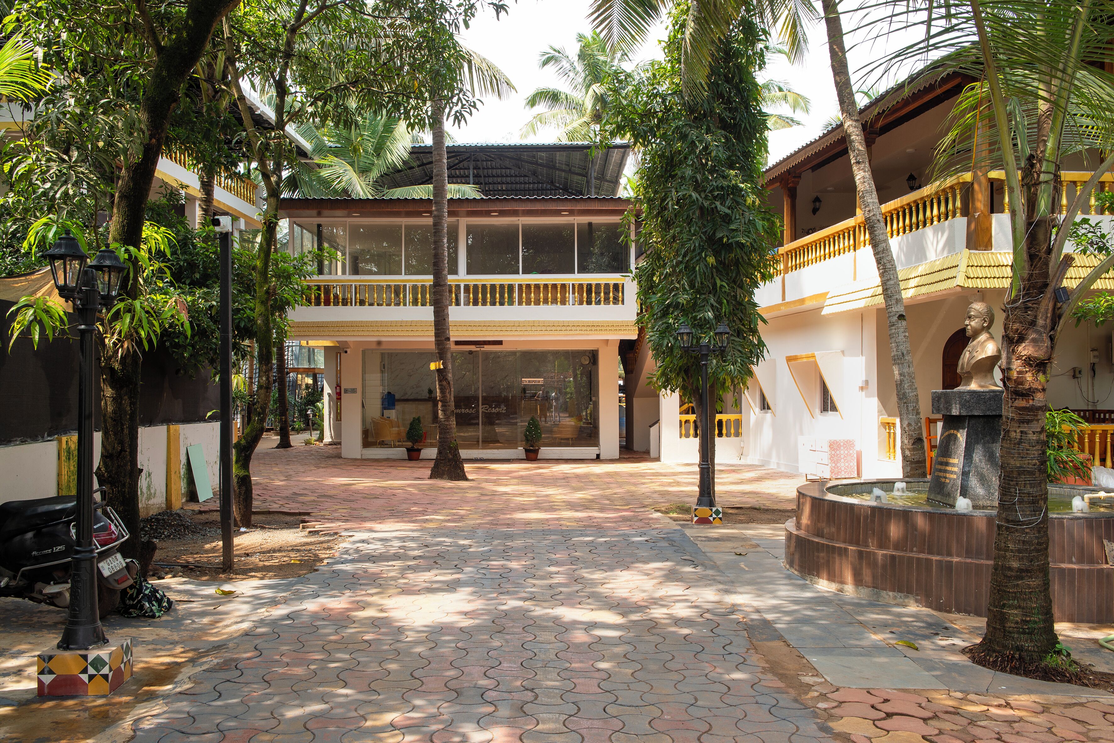 A courtyard with a tiled walkway, palm trees, and a building with balconies.