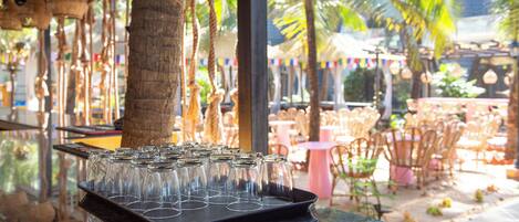 A bar area with a tray of empty glasses, palm trees, and outdoor seating.