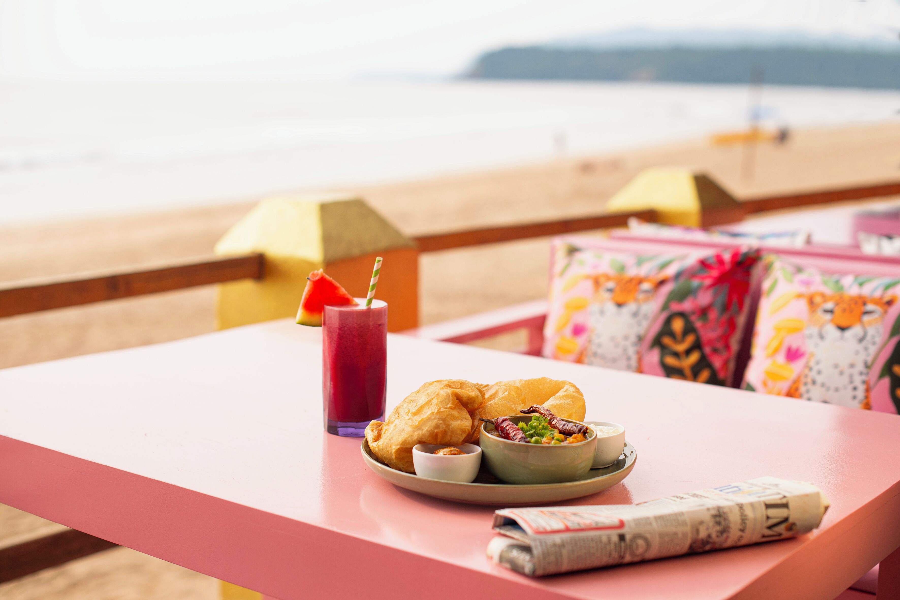 A table with croissants, a bowl of salad, a glass of juice, and a newspaper.