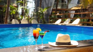 A poolside setting with a drink and a hat on a table, surrounded by lounge chairs and palm trees. - The Rose Goa Beach Resort (Canacona)