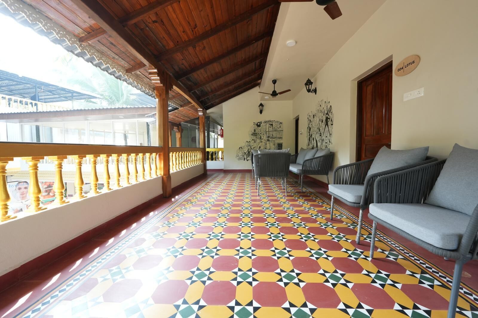 Un balcon abrité doté d’un sol aux motifs géométriques colorés, d’un ventilateur de plafond et d’un coin salon avec des canapés gris.