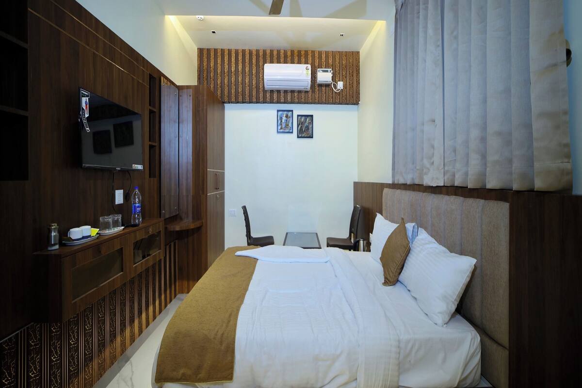 Une chambre d’hôtel équipée d’un lit, d’un bureau, d’une chaise, d’une télévision et d’un appareil de climatisation.