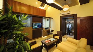A lobby with a reception desk, seating area, and an elevator. - Suthanthira Stay Inn (Thindukkal)