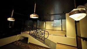 A modern interior with a staircase, metal railings, and pendant lighting. - Suthanthira Stay Inn (Thindukkal)