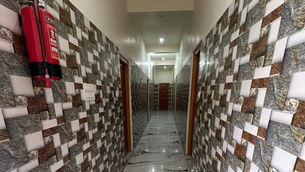A hallway with patterned walls and a marble floor, leading to a door at the end. - Hotel Royal Sainik (Bhatwari)