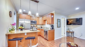 A modern kitchen with wooden cabinets, stainless steel appliances, and a bar area with stools. - Walk to Historic Dtwn St Augustine! Bring Your Pet (St. Augustine)