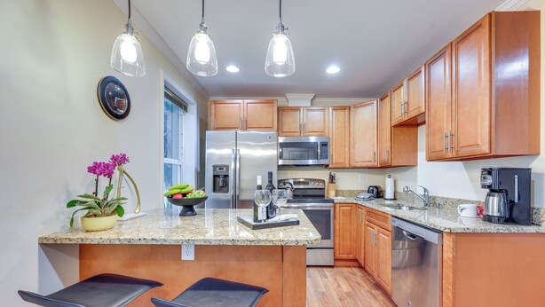 A modern kitchen with wooden cabinets, stainless steel appliances, granite countertops, and pendant lighting. - Walk to Historic Dtwn St Augustine! Bring Your Pet (St. Augustine)