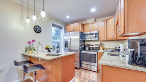 A modern kitchen with wooden cabinets, stainless steel appliances, and a granite countertop. - Walk to Historic Dtwn St Augustine! Bring Your Pet (St. Augustine)