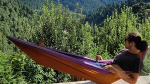 Una persona descansando en una hamaca con vistas a la montaña.