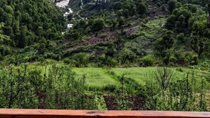 Un paisaje montañoso con un valle, un río y un pequeño edificio a lo lejos.
