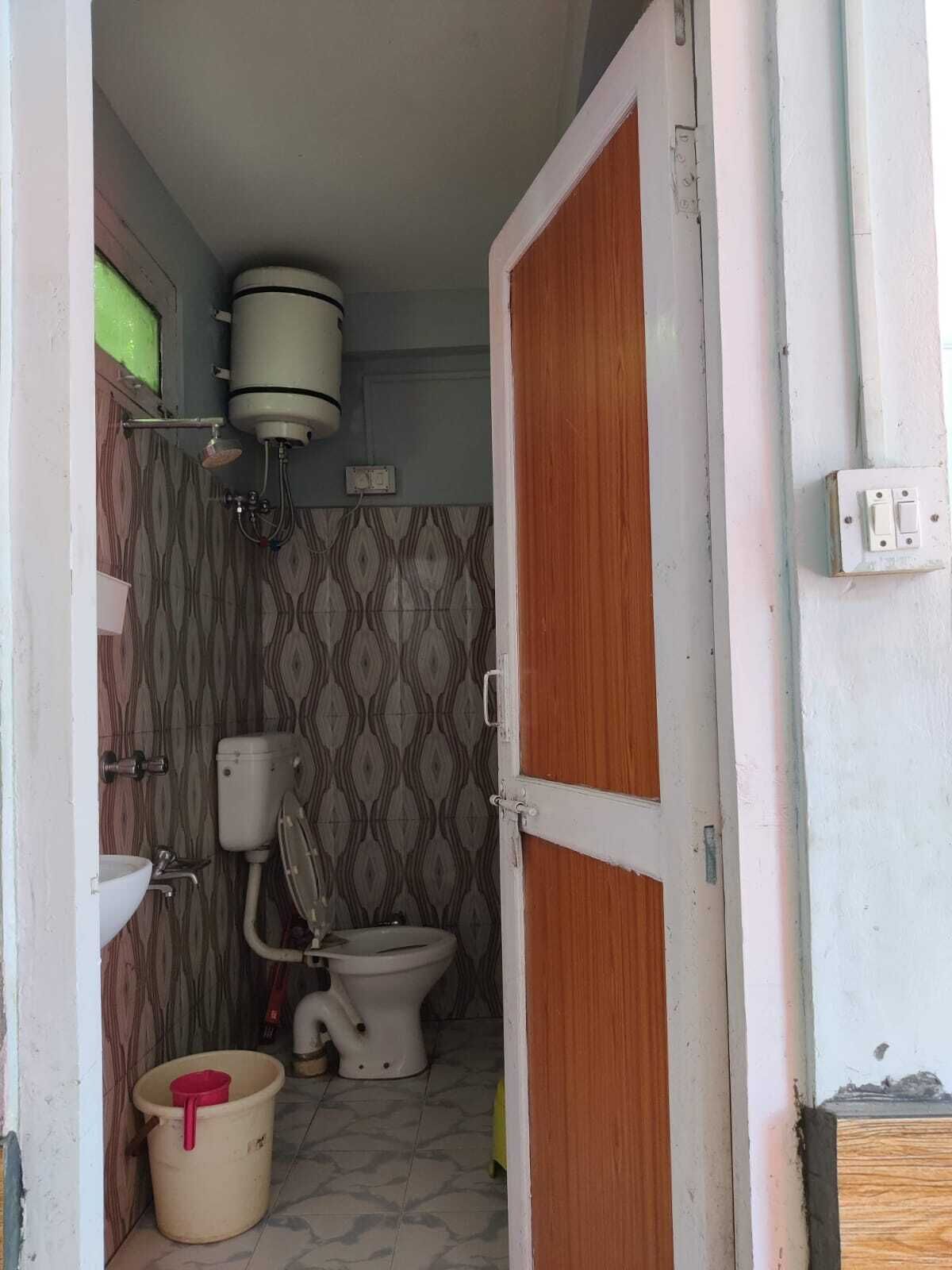 Un bany petit amb vàter, rentapel obert i un dipòsit d'aigua a la paret.