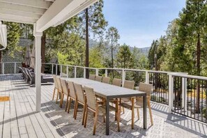Una terrazza esterna coperta con tavolo e sedie, circondata da una ringhiera bianca.
